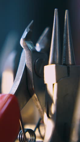 cu: motion along different professional goldsmith pliers against blurred background at bright light extreme close view