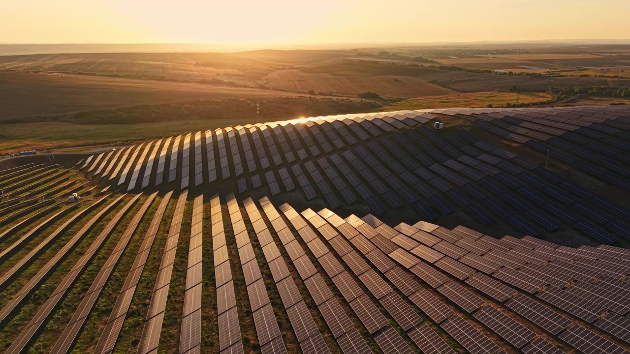 Solpaneler på en stor mark ved solnedgang i et landområde