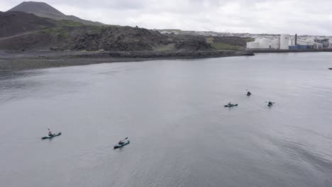 drone volando sobre un grupo de kayakistas oceánicos remando hacia la isla heimaey