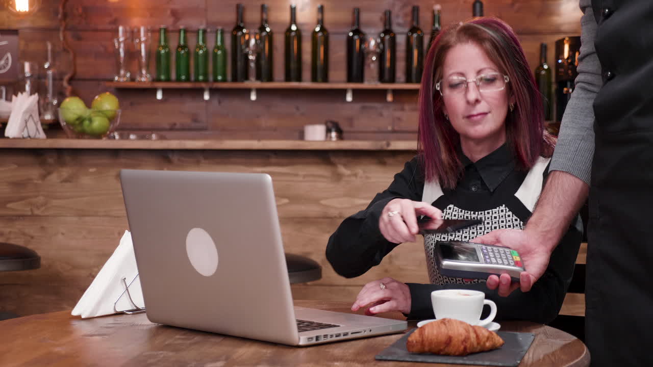 Woman working on laptop in cafe with coffee and croissant