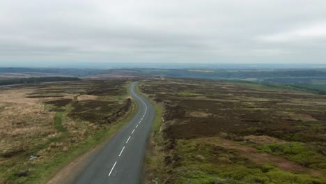 drone flying over empty, twisty scenic driving road in the north yorkshire moors on a cloudy overcast day