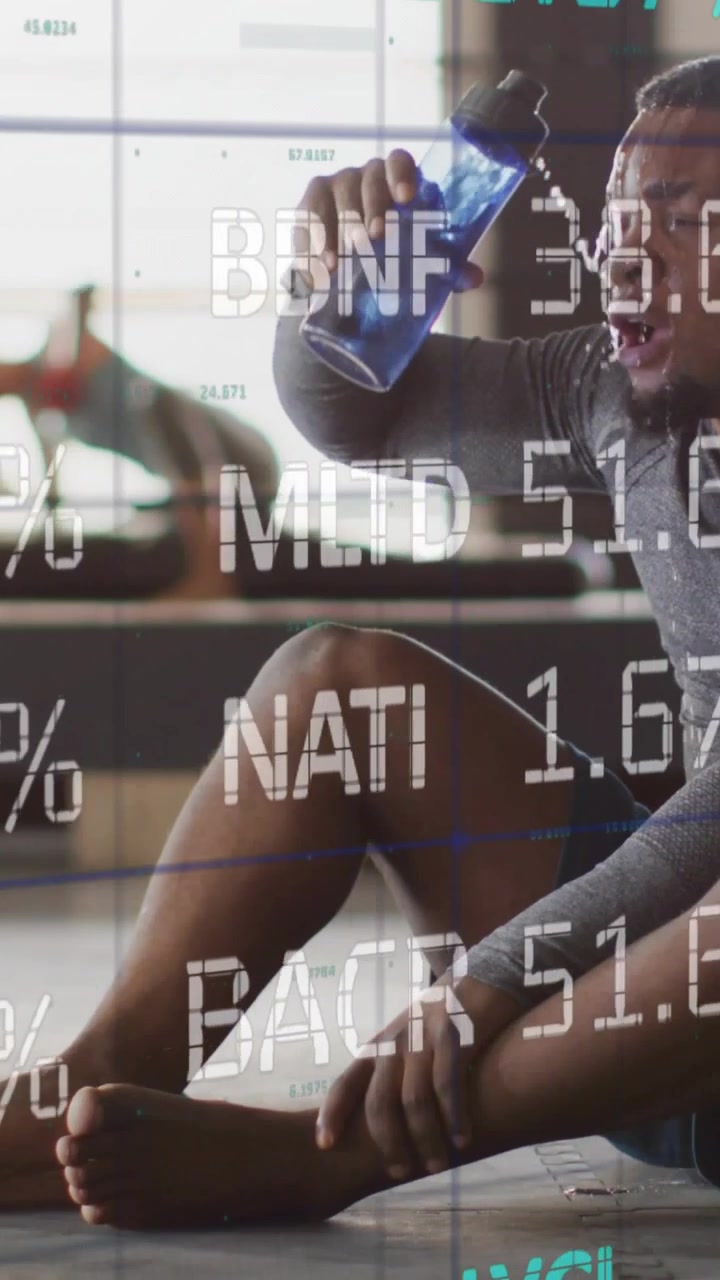 Vertical video: Man cooling in gym grabbing bottle pouring sipping while percent scrolling over him