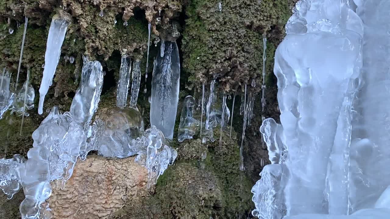 trozo de edificio helado en una pared de piedra con corrientes de agua
