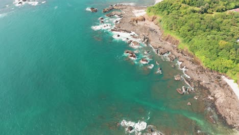 beautiful 4k aerial drone shot of a tropical pacific paradise beach at the seaside coast in costa rica with waves, jungle, rocks and sand