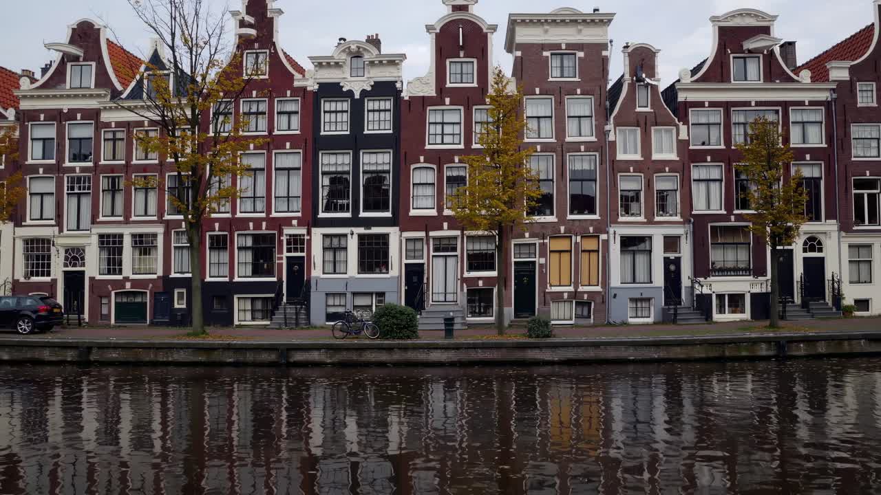 Charming row of historic buildings along a tranquil canal, showcasing architectural details and reflections in the water, creating a picturesque urban scene