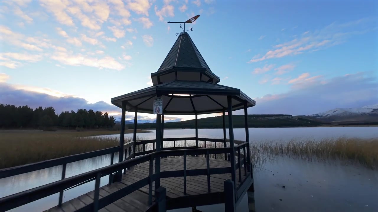Äiti ja nuori tytär kävelemässä kohti laguunin laituria ennen auringonnousua. Nopea FPV-ilmakuvaus sinisellä taivaalla.