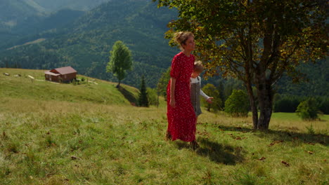 Mother-daughter-looking-mountain-views-walking-green-grass-hill-sunny-day.