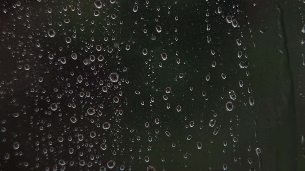 Primer plano de gotas de lluvia deslizándose por una ventana de cristal