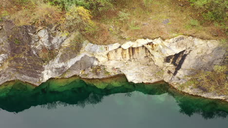 A-top-down-view-over-a-quarry-filled-with-green-water