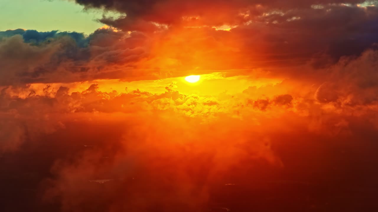 Luftaufnahme: feuriger Himmel und orangefarbene Sonne, die bei Sonnenuntergang mit warmen Farben und Wolken untergeht, einführende Drohnenaufnahme