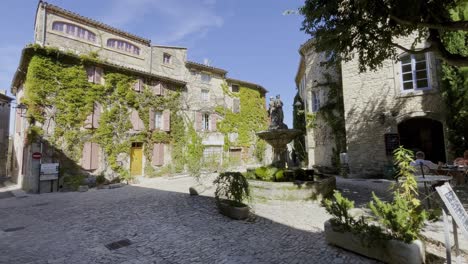 Lugar-Muy-Romántico-En-Francia-Con-Antiguas-Casas-De-Piedra,-Una-Pequeña-Fuente-Y-Un-Hermoso-Ambiente-Bajo-El-Sol.