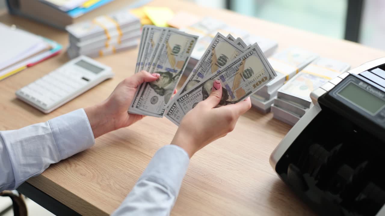 Person Counting Stacks of Hundred Dollar Bills