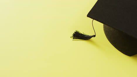 Video-of-graduation-hat-lying-on-yellow-background