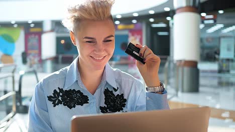 woman shopping online using laptop and credit card in mall cafe