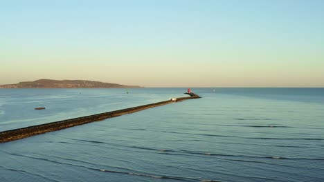 Aerial-flying-over-South-Bull-wall-at-Dublin-Port-during-sunset,-dolly-in