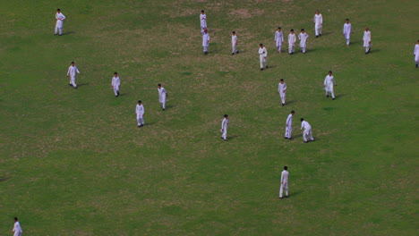 Peshawar,-Pakistán,-Estudiantes-Jugando-Fútbol-Vista-Aérea-Desde-Los-árboles,-Los-Estudiantes-Están-En-Uniformes-Blancos-Shalwar-Kameez,-Hierba-En-El-Suelo