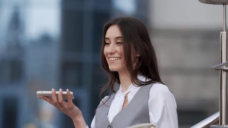 mujer joven feliz en ropa de negocios hablando con un teléfono inteligente
