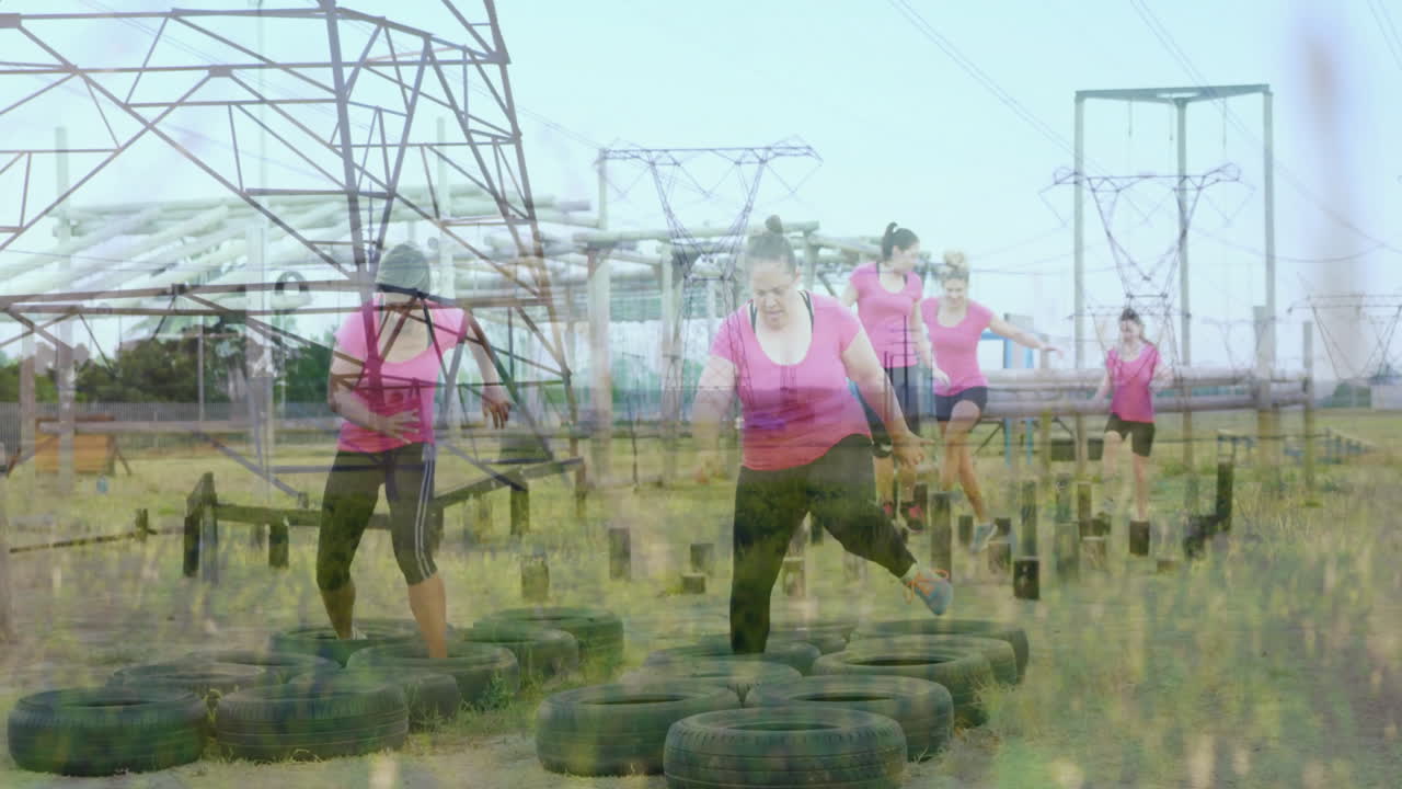 Navigating obstacle course, women in pink shirts tackling tires and power lines
