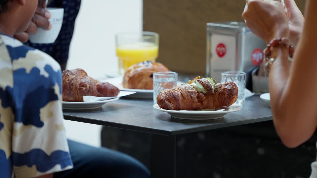 escena anónima que muestra a personas disfrutando de croissants en un café al aire libre
