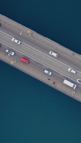traffic of cars on the bridge over the river. blue water. aerial view from above. vertical video