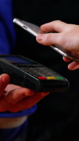 woman paying bill through smartphone using nfc technology