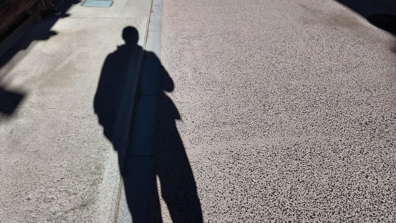 Tourist walking on Narai juku street casting long shadow on sunny morning