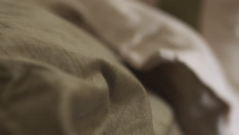 super close up shot of sheets for a bed in soft colors and made of cotton, crooked frame and shallow depth of field with focus changes