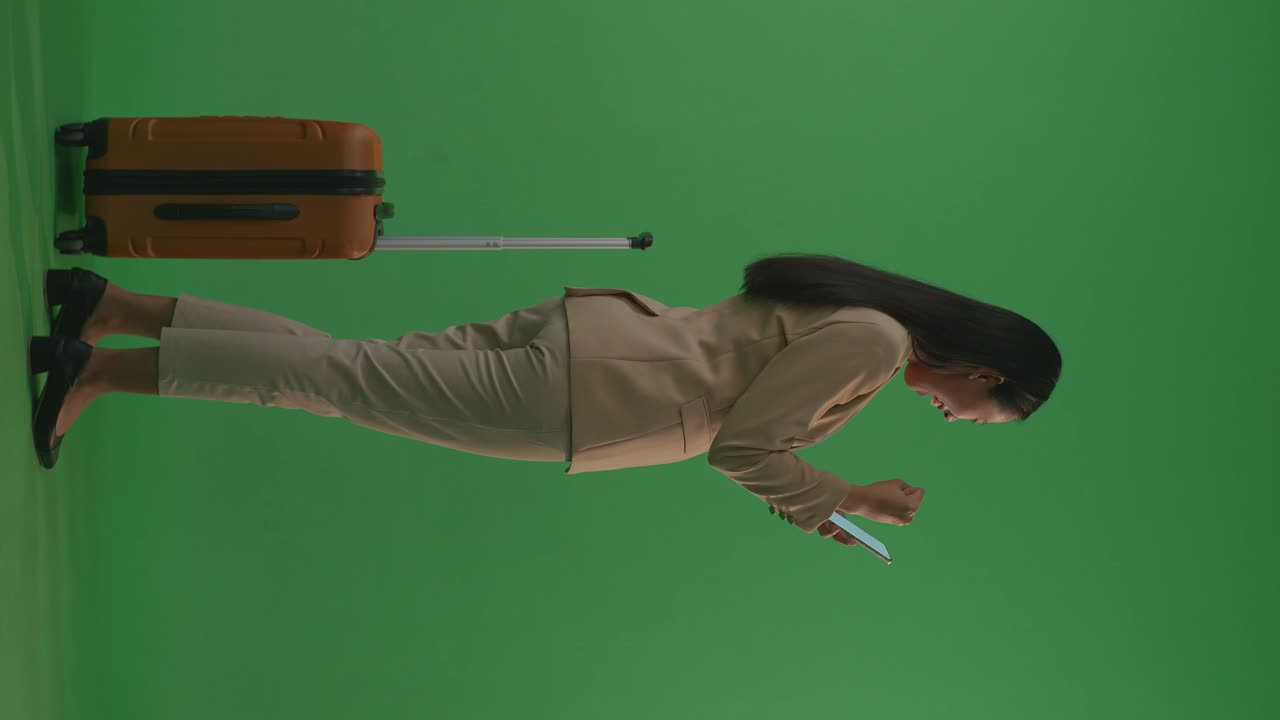 mujer de negocios mirando el teléfono con una maleta.