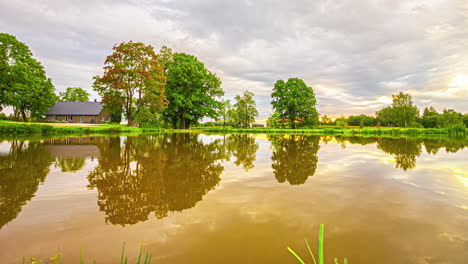 Gelassenheit-Bei-Sonnenaufgang:-Wolken,-Bauernhaus-Und-Spiegelnder-Teich-Im-Zeitraffer