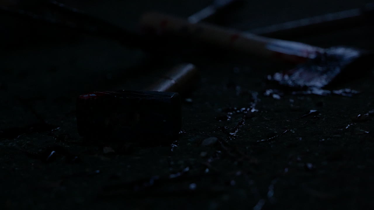 las luces de la policía se acercan gradualmente a la escena del crimen con un martillo y un hacha ensangrentados tirados en el suelo en medio de salpicaduras de sangre
