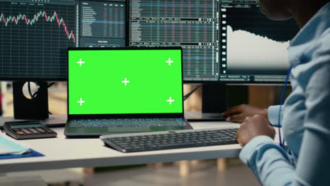 financial analyst at work doing research using green screen laptop