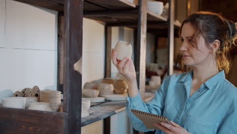 woman examining handmade pottery in her studio