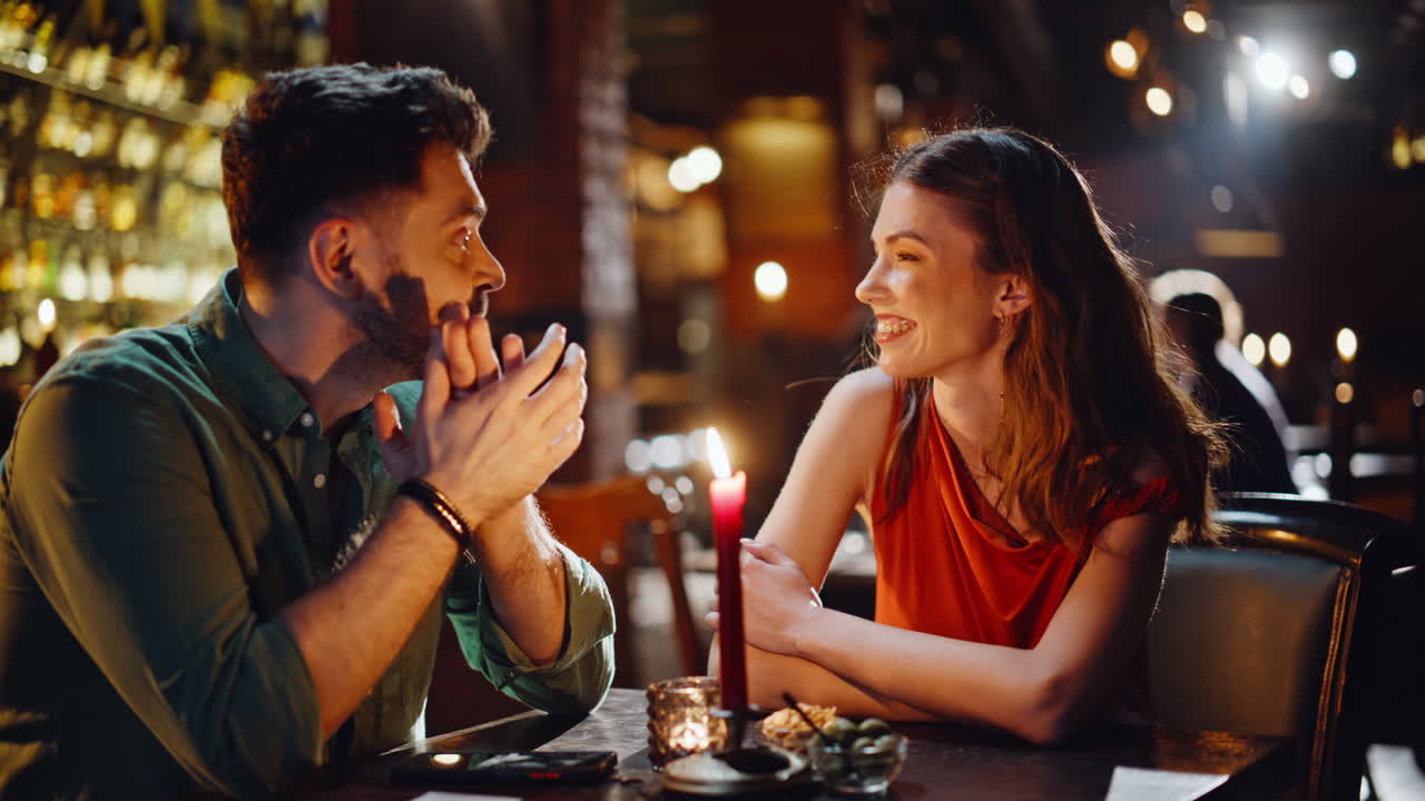 Due amici che guardano il menu all'interno di un caffè buio, primo piano. Coppia felice che discute