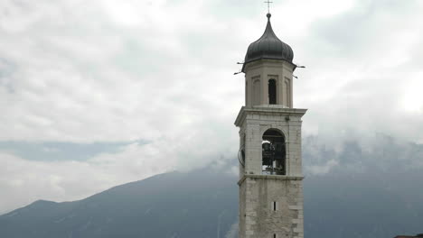 Campanada-En-La-Torre-De-Una-Iglesia-Ubicada-En-Un-Lugar-Celestial-Con-Montañas-Majestuosas-Y-Nubladas-En-El-Fondo