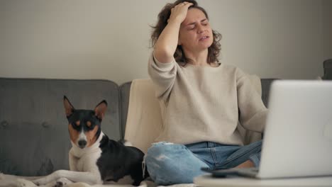 a woman having a migraine attack while works on a laptop