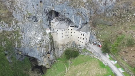 drone shot of mysterious predjama castle, built in a cave mouth in the mountains of slovenia