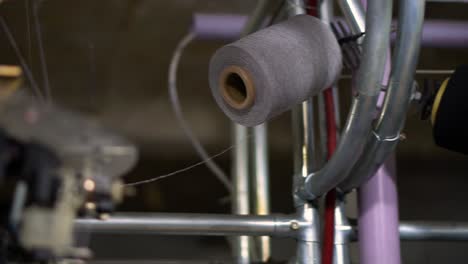 Close-up-shot-of-Spools-with-grey-thread-at-rewinding-machine-video---Close-up-parts-of-the-machine-with-threads,-the-Production-process-in-a-garment-factory,-automated-process