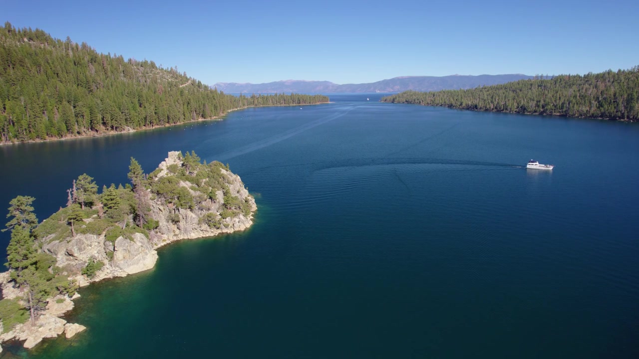 Riprese con drone che sorvolano l'isola di Fannette con una barca che crea una scia curva nella Baia di Smeraldo.