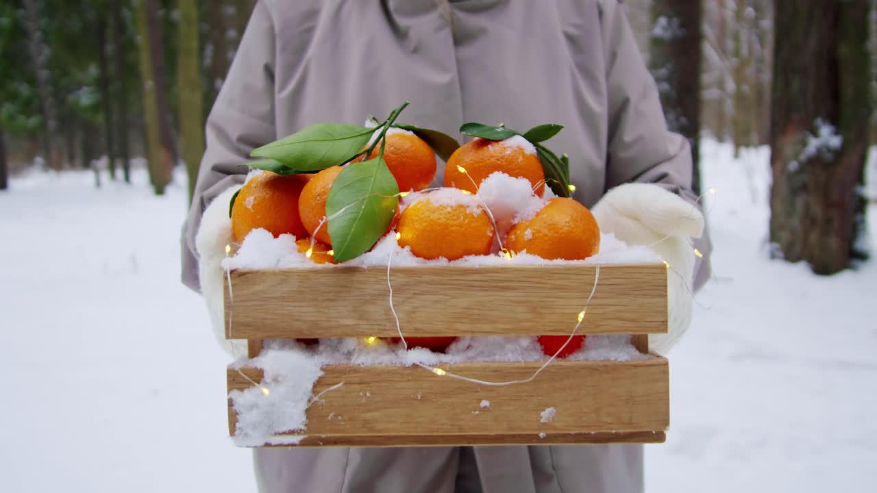 눈 인 숲 에서 눈으로 인 만다린 오렌지 의 나무 상자 를 들고 있는 여자