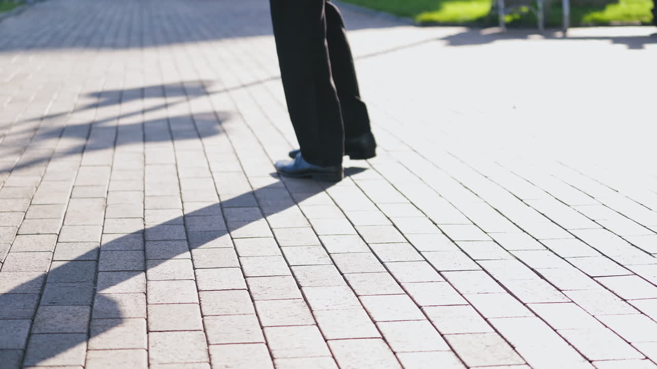 Feet of the businessman walking outdoors. Legs of a man in black trousers and shoes walking nervously up and down the street. Close-up.