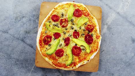 baked pizza with avocado, cherry tomato and olive toppings