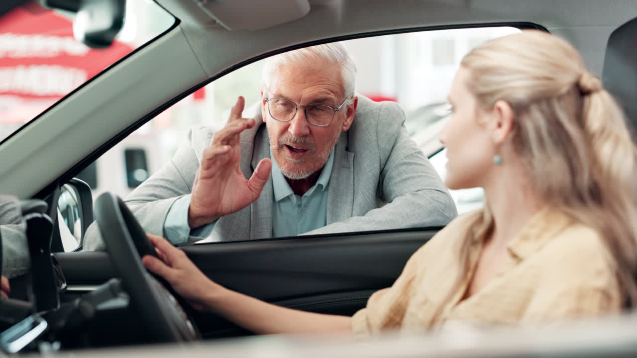 Woman adjusts rearview mirror in new car with salesman