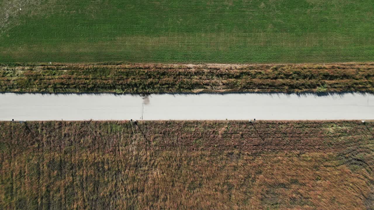 드론은 콘크리트 도로를 포착합니다. 낮에는 은 잔디을 갈라놓고 관리되지 않은 을 습니다.