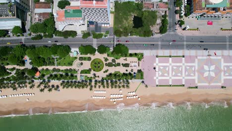 vista aérea de gran altitud de arriba hacia abajo de la carretera costera con tráfico de motocicletas y automóviles conduciendo en nha trang con una hermosa vista de la playa de arena blanca y el océano verde turquesa en un día soleado