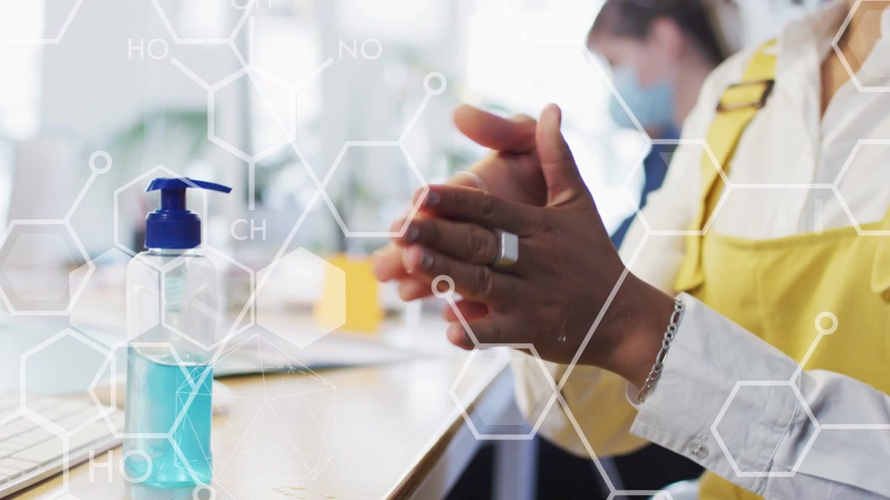 Worker reaching for pump, pumping gel and rubbing hands for office hygiene, hexagonal over hands
