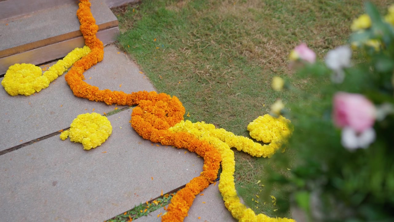 Ghirlande di fiori di calendula disposte su gradini esterni con erba fresca e fioriture.