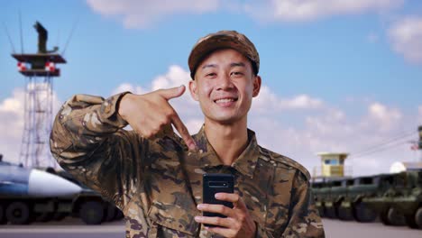 smiling soldier using smartphone at airbase