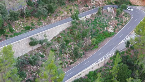 Vista-Aérea-De-Un-Motociclista-Conduciendo-Una-Carretera-Torcida-De-Montaña-En-Las-Montañas-De-Mallorca