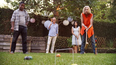 grupo de amigos maduros jugando al croquet en el patio trasero juntos