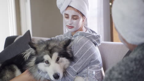 woman with facial mask cuddling a dog on a sofa